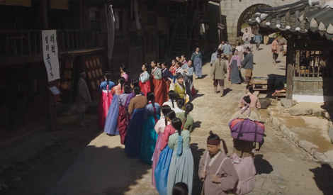 ‘서책 빌려드립니다’라고 적힌 세책점 건물 앞에 모여든 조선시대 군중의 모습. 한복을 입은 20여명의 남녀들이 세책점 앞에 모여있다.