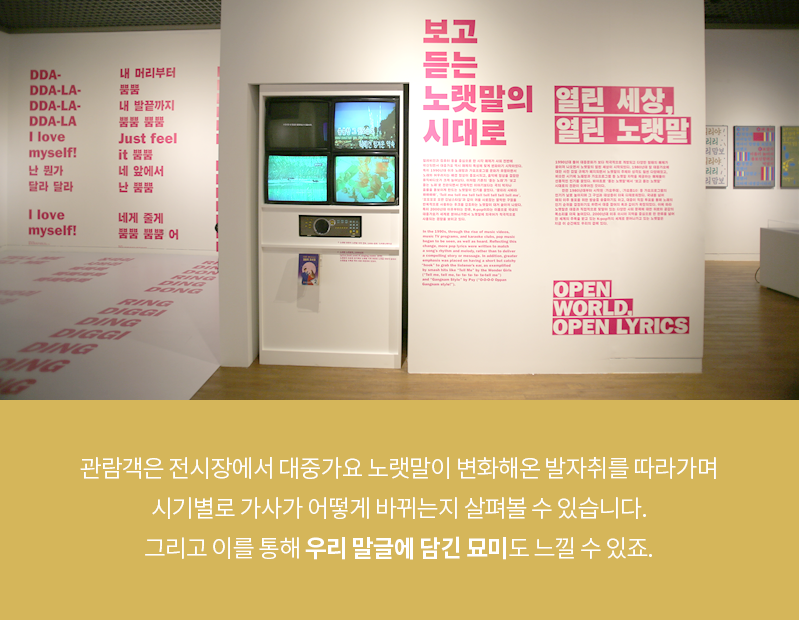 카드뉴스 세 번째 장. 전시장 벽면 사진으로 벽 한쪽에는 노래방 기계 노래방 TV 화면이 설치되어 있으며 그 옆에 전시 내용이 적혀있다. ‘보고듣는 노랫말의 시대로’, ‘열린 세상, 열린 노랫말’, ‘OPEN WORLD, OPEN LYRICS’ 등의 문구가 커다랗게 적혀 눈에 띈다. 카드뉴스 내용은 ‘관람객은 전시장에서 대중가요 노랫말이 변화해온 발자취를 따라가며 시기별로 가사가 어떻게 바뀌는지 살펴볼 수 있습니다. 그리고 이를 통해 우리 말글에 담긴 묘미도 느낄 수 있죠.’이다. 