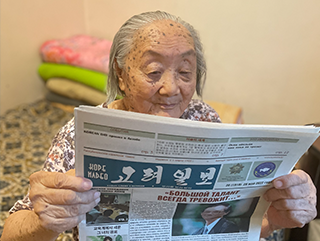 「고려일보」를 들고 읽고 있는 할머니의 모습이다.