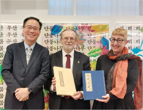 <「훈민정음 해례본」과 「훈민정음 언해본」 증정 현장 사진이다. 왼쪽부터 김영수 한글박물관장, 피오트르 타라하 동양학부 학장, 안나 파라돕스카 한국어문학과장이 정면의 카메라를 향해 자세를 취하고 있다. 