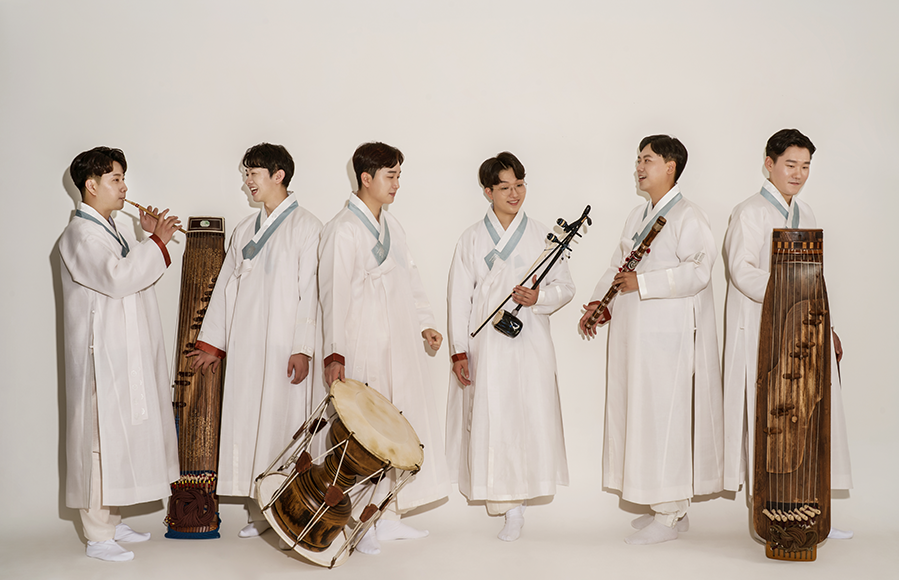 출연단체 전통음악집단 샛의 단체 사진이다. 흰색 전통의상을 입은 여섯 명의 단원이 일렬로 나란히 서서 제각각 전통 악기 한 개씩을 들고 있다.