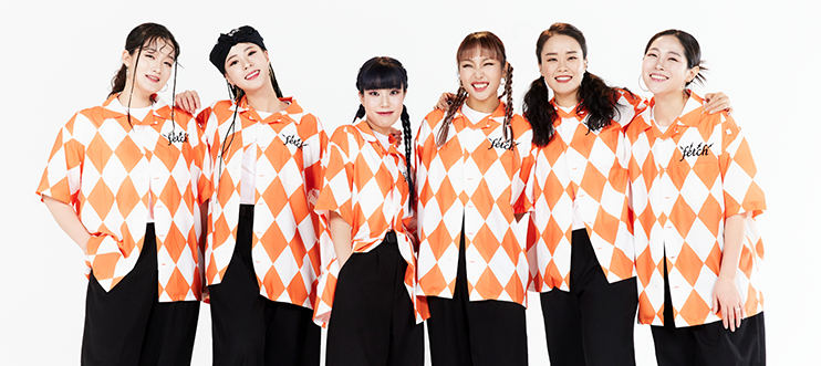 출연단체 롤링핸즈의 단체 사진이다. 흰색과 주황색이 타일 모양으로 섞인 상의와 검은색 바지를 맞춰 입은 6명의 여성이 정면을 바라보고 있다.