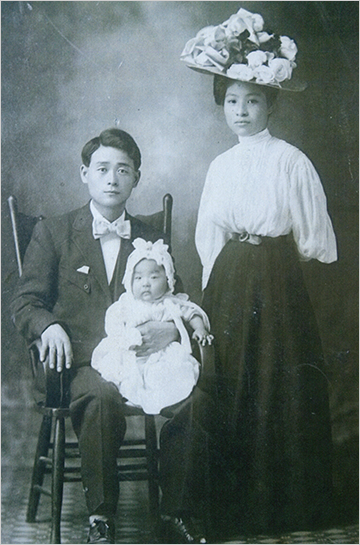 1903년 미국 하와이로 이민을 떠났던 김장연의 가족사진. 김장연은 장남 김영걸을 안고 의자에 앉아있고, 오른쪽엔 그의 아내 최심성이 꽃 모양으로 꾸며진 큰 모자를 쓰고 정면을 바라보고 있다.