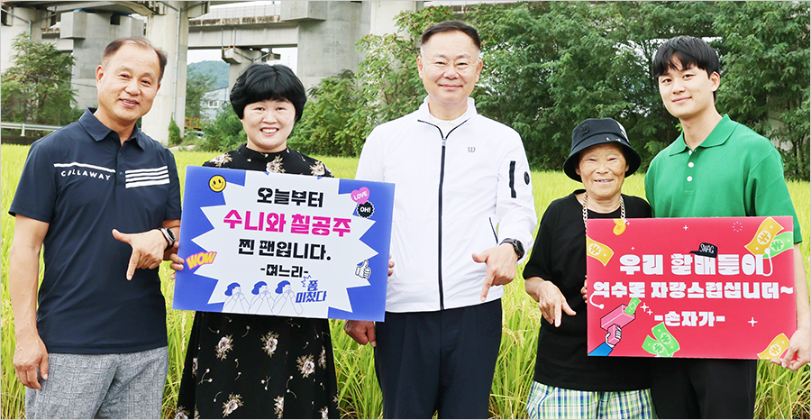 박점순 할머니, 김재욱 칠곡군수, 박점순 할머니 가족들이 기념사진을 찍고 있다. 검은색 옷을 입은 며느리는 ‘오늘부터 수니와 칠공주 찐팬입니다’라고 적힌 판과 초록색 옷을 입은 손자는 ‘우리 할매들이 억수로 자랑스럽습니더~’라고 적힌 판을 들고 있다.