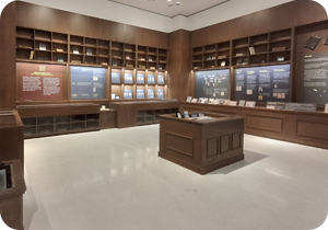 ‘어린이 나라’ 전시 전경 사진이다. 벽면은 고급스러운 나무 책장으로 채워져 있고, 그 안에 설명 문구가 적혀있는 전시 패널들과 책 등이 전시되어 있다. 가운데에는 나무로 된 네모난 진열대가 놓여있다. 사진 하단에는 주황색 박스 안에 ‘슬기로운 한글생활’ 문구가 적혀있다. 그 아래에는 기사의 제목 ‘가족과 함께 문화생활을 즐기고 싶다면? 공주에서 열리는 한글 전시 보러 오세요!’가 쓰여있다.